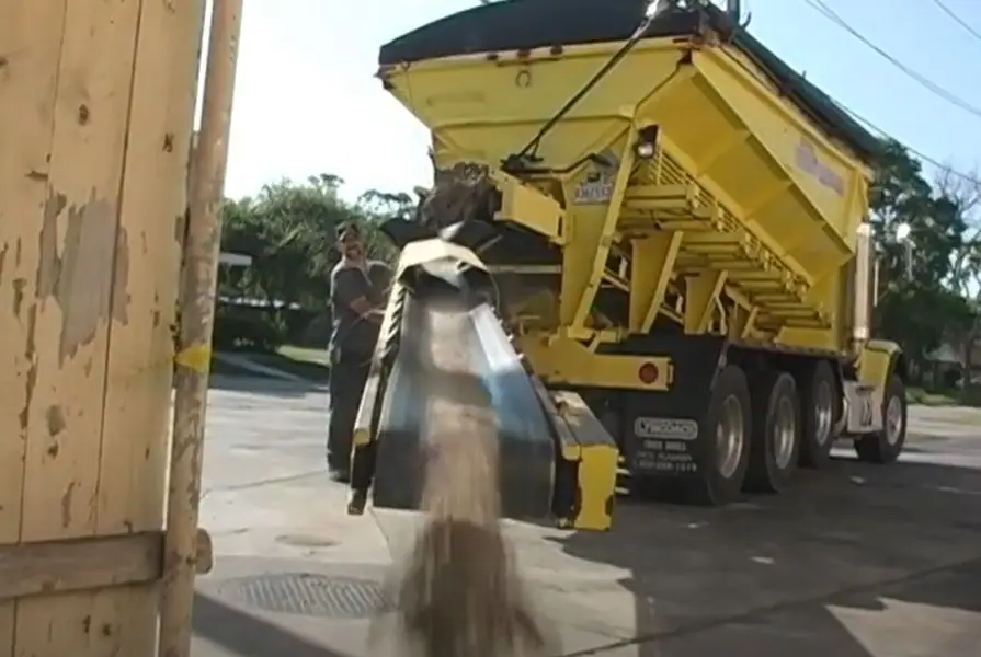 Sand pouring from the conveyor of a Peterson sand truck on a job